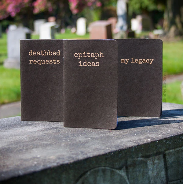 Three pocket-sized notebooks, each with a different inscription in serif font - from left to right, 
